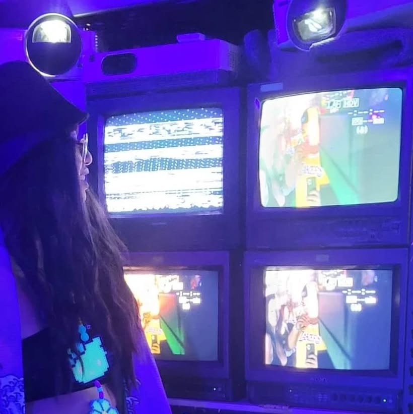over the shoulder shot of a girl looking at multiple retro TVs with a purple hue